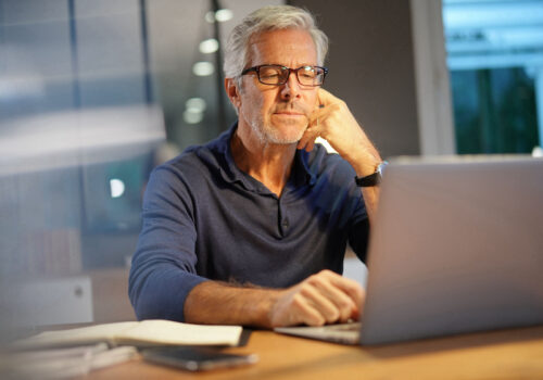 Portrait of senior man with grey hair connected with laptop